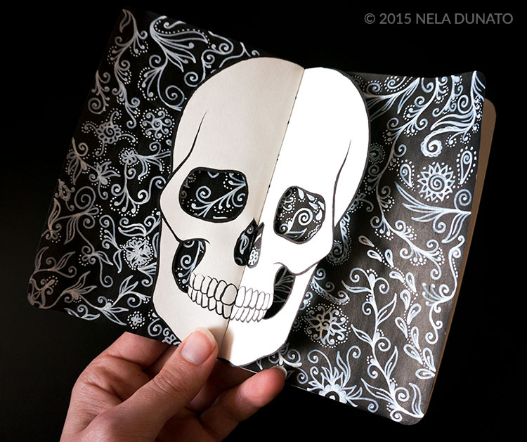 Paper-cut skull over a page of ornament doodles in a sketchbook